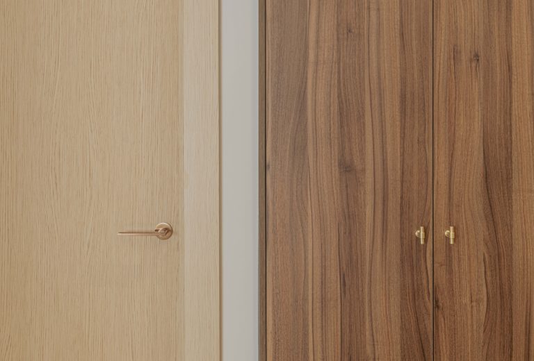Detalle de puertas en madera clara y oscura con herrajes dorados en C105.
